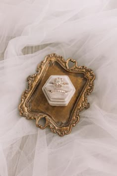 an ornate gold and white brooch with a diamond in the center on a tulle background