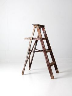 an old wooden ladder leaning against a white wall