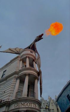 an orange object is flying in the air near a tall building on a cloudy day