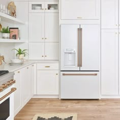 a kitchen with white cabinets and gold trim on the oven, stove top and refrigerator