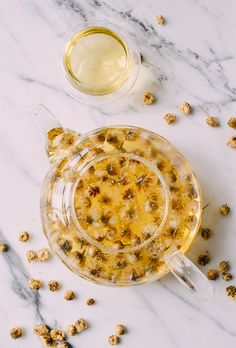 a glass bowl filled with food sitting on top of a white counter next to a cup