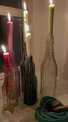 three bottles with candles in them sitting on a table next to a window sill