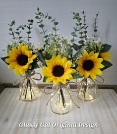 three glass vases with sunflowers and baby's breath