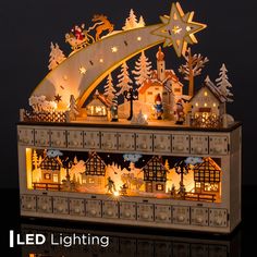 an illuminated christmas village with santa and his sleigh on the roof is shown