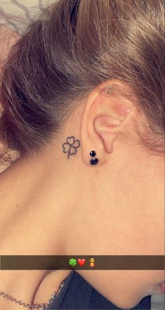 the back of a woman's neck with four leaf clovers behind her ear