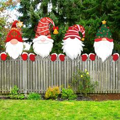 three christmas gnomes on top of a wooden fence