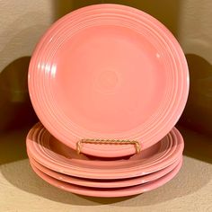 a stack of pink plates sitting on top of each other in front of a wall