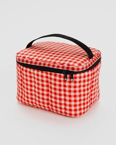 a red and white checkered lunch bag on a white surface with black straps,