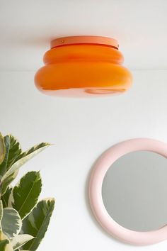 a round mirror sitting on top of a white table next to a potted plant