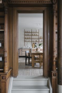 an open door leading to a kitchen and dining room with wooden stairs in front of it