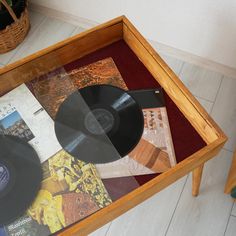 a wooden table topped with a glass top covered in vinyl records