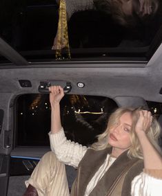 a woman sitting in the back seat of a car with her hand on the door handle