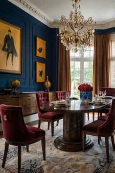 a formal dining room with blue walls and chandelier hanging from the ceiling, surrounded by red velvet upholstered chairs