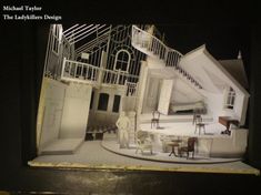 a model of a living room and kitchen in a house with stairs leading up to the second floor