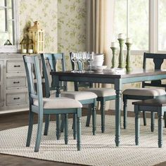 a dining room table with four chairs and a rug on the floor in front of it