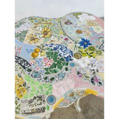 an artistically designed table with flowers and leaves on it's top, sitting on the floor