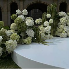 white flowers and greenery are arranged on a table