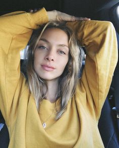 a woman sitting in the back seat of a car with her hands on her head