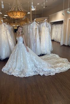 a woman is standing in front of some wedding gowns