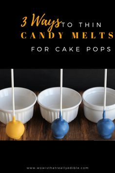 three white bowls with blue and yellow candy popss in them on a wooden table