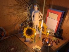 a table topped with sunflowers and candles next to a framed image on the wall