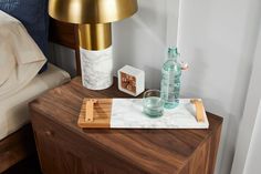 a wooden table topped with a bottle of water next to a lamp