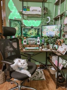 a white cat sitting on top of a black chair in front of a computer desk