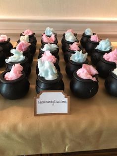 a table topped with black caulders filled with pink and blue frosted marshmallows