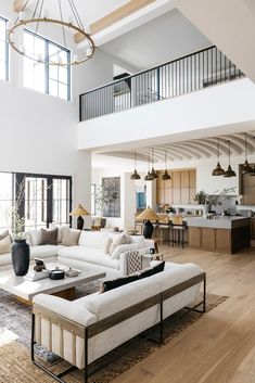 a living room filled with white furniture and lots of windows on top of the ceiling