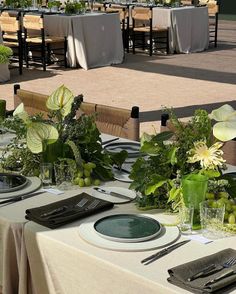 a table set with place settings and flowers in vases on top of the tables