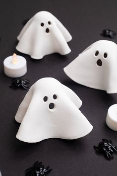 some white ghost candles are on a black surface