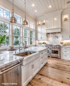 a kitchen with white cabinets and marble counter tops, stainless steel appliances and wooden floors