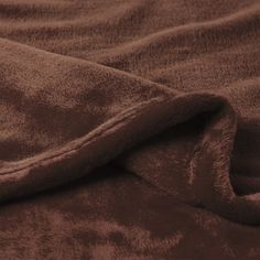 a brown blanket is laying on top of a bed with the sheets pulled back and folded down