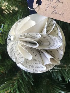 a book page ornament hanging from a christmas tree with a tag on it