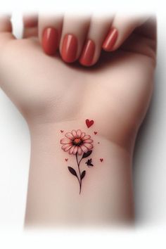 a woman's wrist with a pink flower and hearts tattoo on the left side