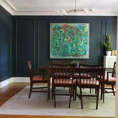 a dining room table with chairs and a painting on the wall