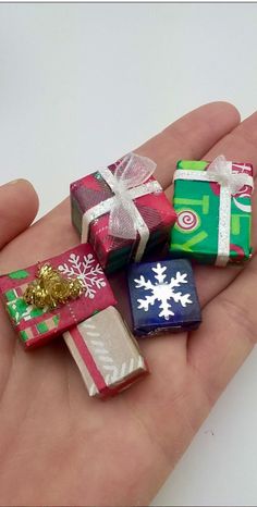 small presents are wrapped in wrapping paper and tied with ribbons on the palm of a person's hand