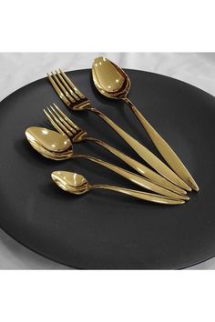 a black plate topped with gold colored utensils