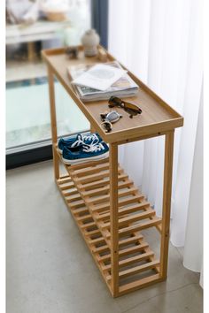 a wooden table with several pairs of shoes on it next to a mirror and window