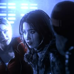 two women standing next to each other in front of a blue light with the lights on