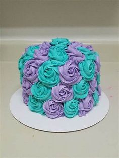 a cake with purple and blue frosting roses on the top is sitting on a white plate