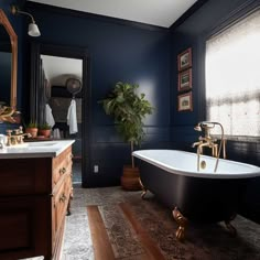 a bath tub sitting next to a sink under a mirror in a room with blue walls