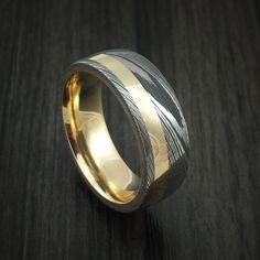 two tone gold and silver wedding ring with wavy lines on the inside, sitting on a wooden surface