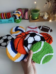 a hand is pointing at several crocheted coasters on a table with other items