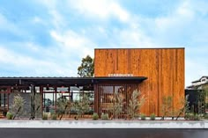 the building has wooden panels on it's sides and is surrounded by greenery