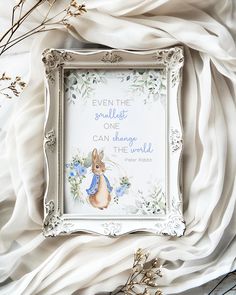 a white frame sitting on top of a bed next to dried flowers and plants with a quote written in it