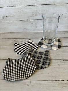 three gingham checkered bibs next to a glass on a wooden table