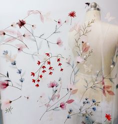 a mannequin with flowers on it next to a sheer fabric covering the torso