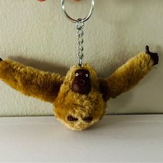 a stuffed animal hanging from a keychain on a white surface with two hands