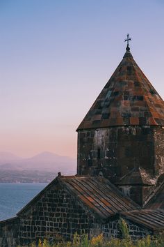 an old brick church with a cross on it's steeple overlooking the ocean